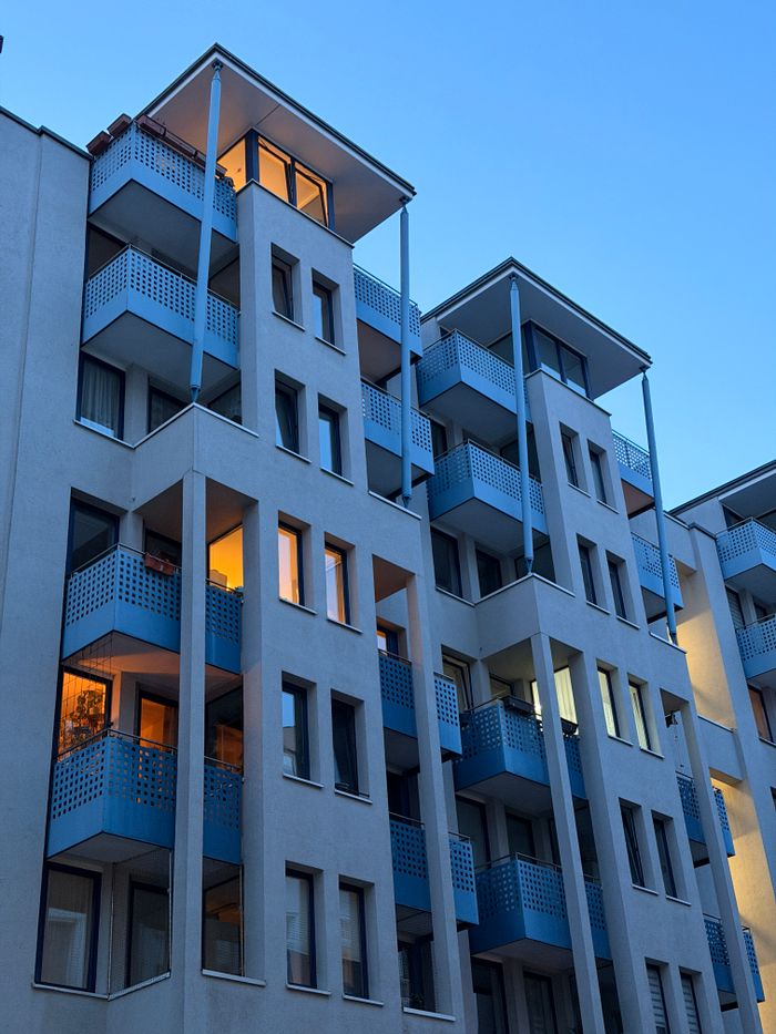 about-02 Contemporary apartment buildings in Berlin with blue balconies illuminated by sunrise light.