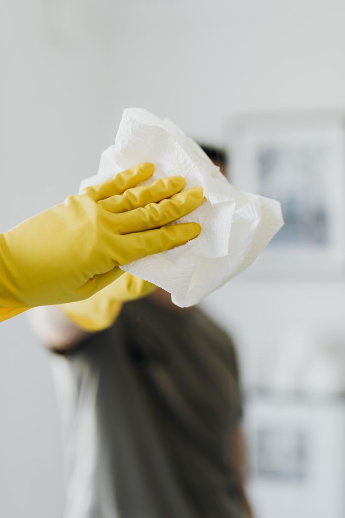 why-choose-us-03 Anonymous male wearing yellow latex gloves and dark t shirt wiping mirror in bathroom with paper napkin