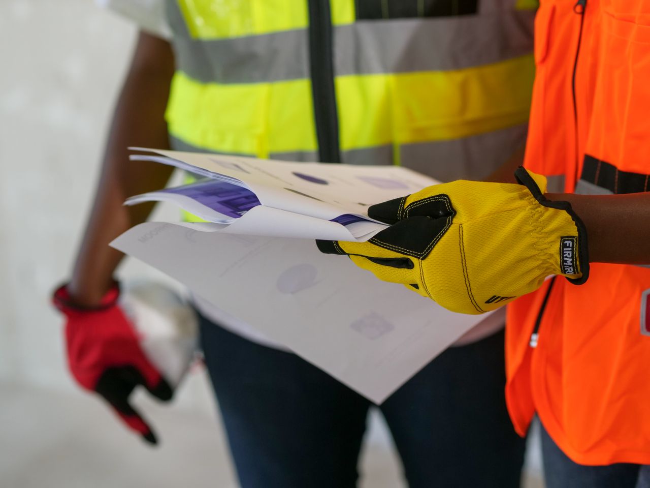 services-05 Close-up of construction workers reviewing documents wearing protective gear. Safety-focused interaction.