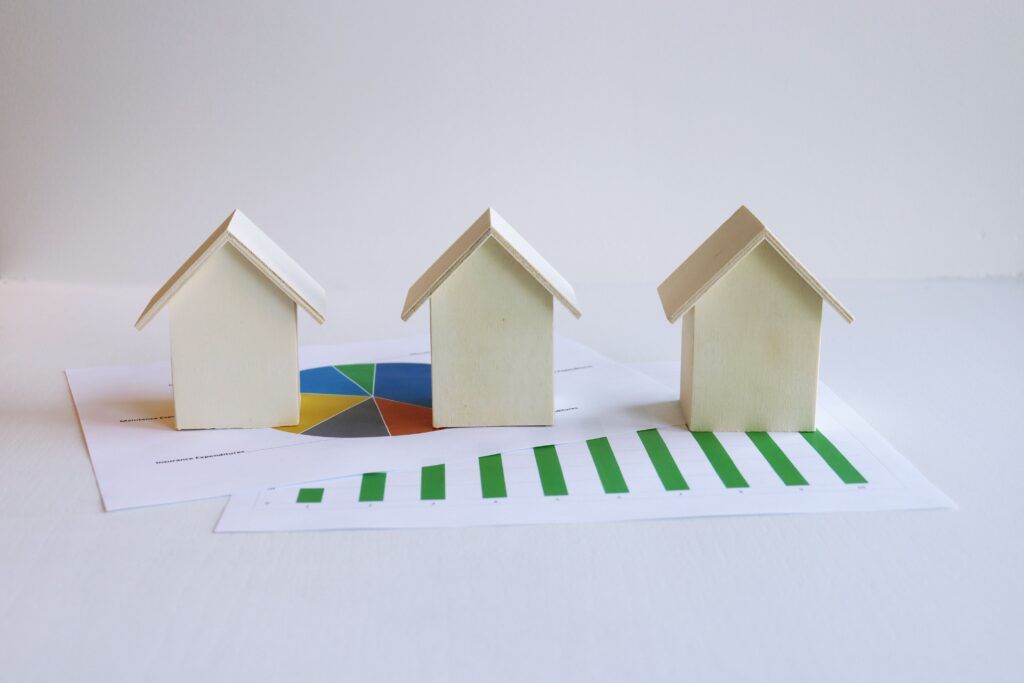 Wooden model houses on graphs depict real estate market analysis and trends.